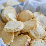 Die Heidesand Plätzchen mit Marzipan sind ein echter Klassiker (nicht nur) zu Weihnachten und sehr beliebt. Sie sind super einfach zu backen und schmecken der ganzen Familie. Die Heidesand Kekse werden als Rolle geformt, in Hagelzucker gerollt und dann in Scheiben geschnitten. Dann backst du die Marzipan Plätzchen im Ofen. Nur so lange, dass die schön mürbe sind und auf der Zunge zergehen. Ich stecke total im Weihnachtsfieber und habe direkt wieder gebacken, es gibt leckere Weihnachtskekse. Da ich nicht weiss wie lange ich die Zeit noch nutzen kann in meiner Schwangerschaft, habe ich in diesem Jahr bereits deutlich früher angefangen für Weihnachten zu backen. Es gibt echte Klassiker und neue Rezepte, die ich mir zusammengestellt habe. Alte Rezepte neu interpretiert sozusagen. Aber bei den Heidesand mit Marzipan habe ich nicht lange herum experimentiert. Es gibt bereits Schoko-Orange Heidesand auf dem Blog, die vor einigen Jahren sehr spontan entstanden sind. Die Heidesand Plätzchen mit Marzipan sind ein beliebter Klassiker, der hier auf dem Blog definitiv noch gefehlt hat. Mir schmecken die zarten Marzipan Plätzchen besonders gut. Und das Rezept ist wunderbar einfach - es handelt sich bei den Heidesand um zartes Buttergebäck mit Marzipan, das auf der Zunge zergeht. Im Ernst, die sind einfach super lecker! Diese Zutaten brauchst du zum Backen der Marzipan Heidesand (genaue Mengenangaben findest du am Ende des Beitrags) weiche Butter Puderzucker Marzipanrohmasse Vanillezucker Mehl Eier Hagelzucker So einfach backst du zarte Marzipan Heidesand Kekse, die auf der Zunge zergehen Tipps: Kühlzeit einplanen Damit sich der Teig gut verarbeiten und in Scheiben schneiden lässt, sollte er in Rollen geformt über Nacht im Kühlschrank ruhen. Teig einfrieren - wenn du du heute bereits die Kekse backen möchtest, kannst du direkt mehr Teig zubereiten und einfrieren So bewahrst du die Marzipan Heidesand auf Am besten packst du die Marzipan Heidesand-Plätzchen direkt nach dem Abkühlen in Keksdosen. So bleiben sie schön knusprig und kannst sie die nächsten 3-4 Wochen genießen (wenn denn so lange welche übrig bleiben). Kann man Heidesand-Teig einfrieren? Wer gleich etwas mehr Teig anrühren möchte oder noch Teig übrig hat, kann diesen auch ganz praktisch einfrieren. Dafür die fertigen Teigrollen in Klarsichtfolie wickeln und in das Gefrierfach legen. So kannst du den Teig nach Belieben auftauen und wie unter Schritt 3 fertig zubereiten. Einmal Arbeit, mehrfacher Heidesand-Genuss.