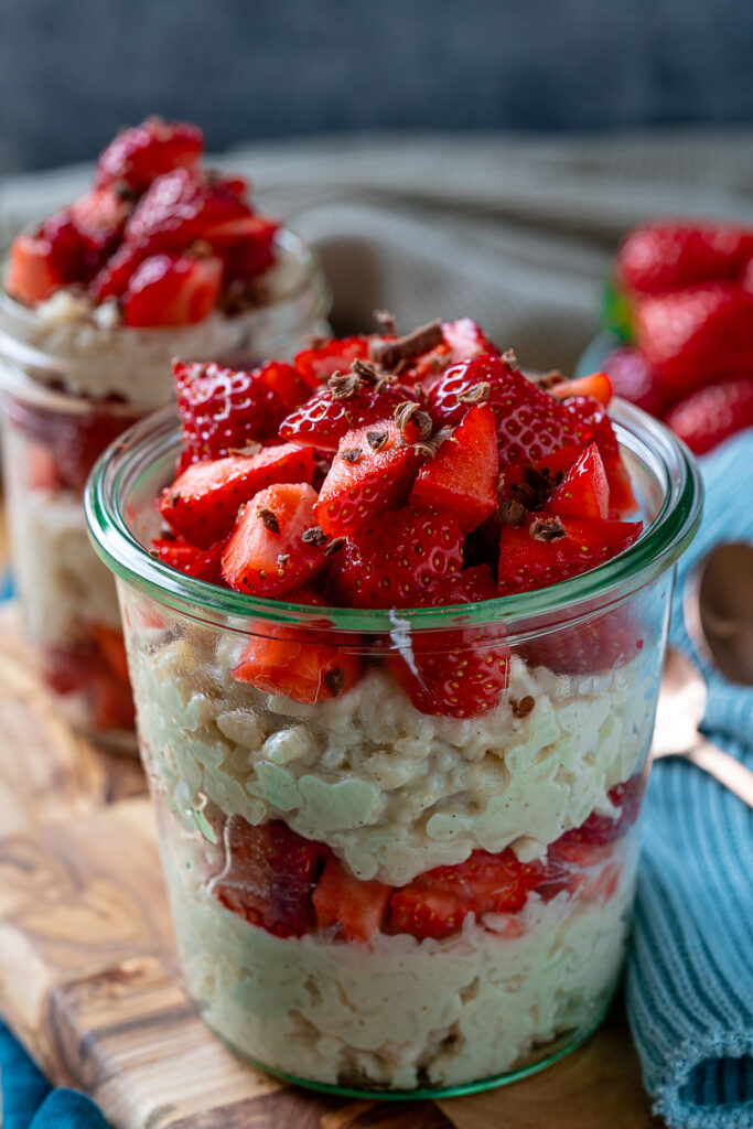 Veganer Milchreis mit Erdbeeren und Raspelschokolade im Glas anrichten